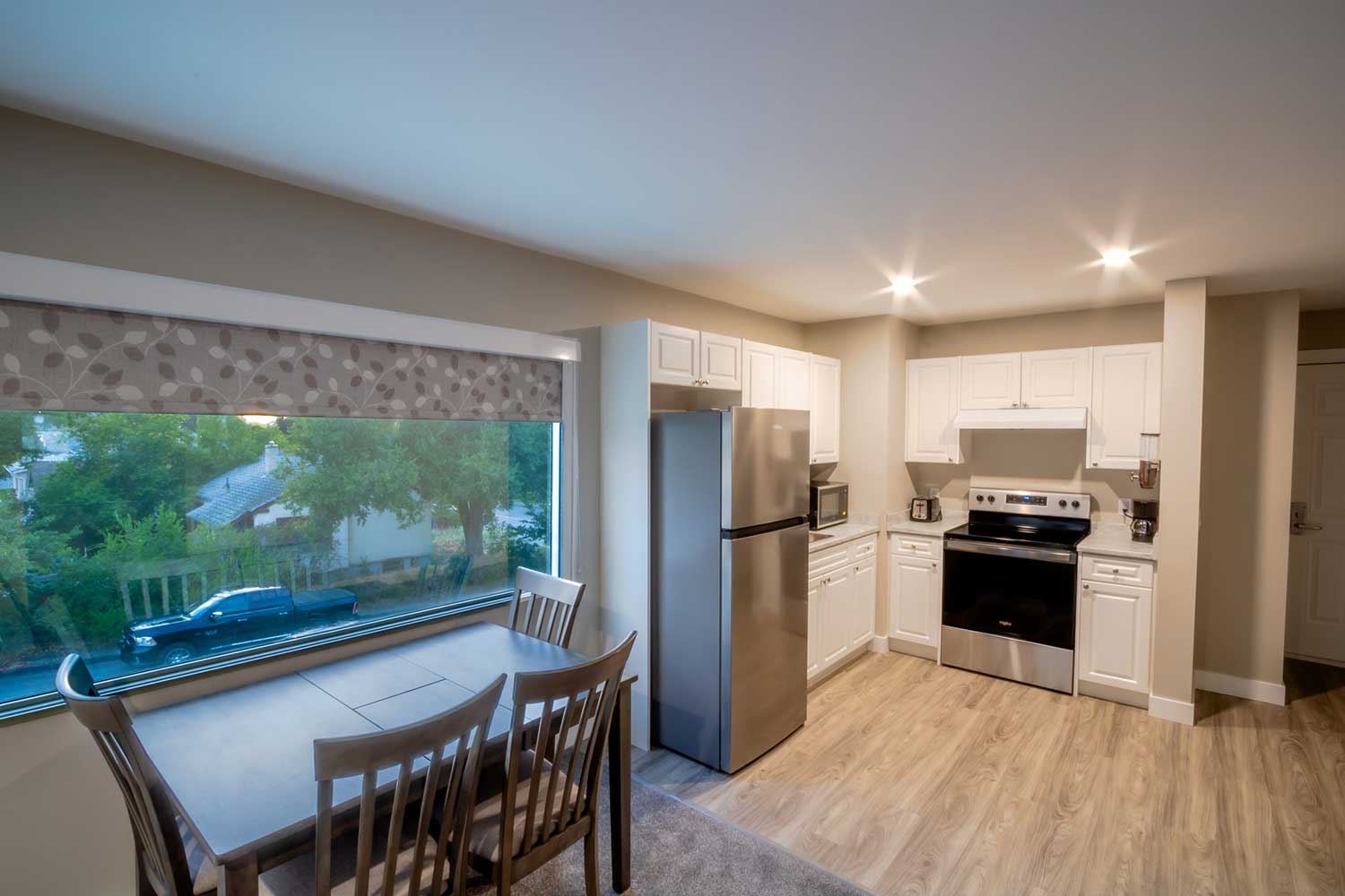 A kitchenette of a junior suite. Bright new appliances, and a dinette table.