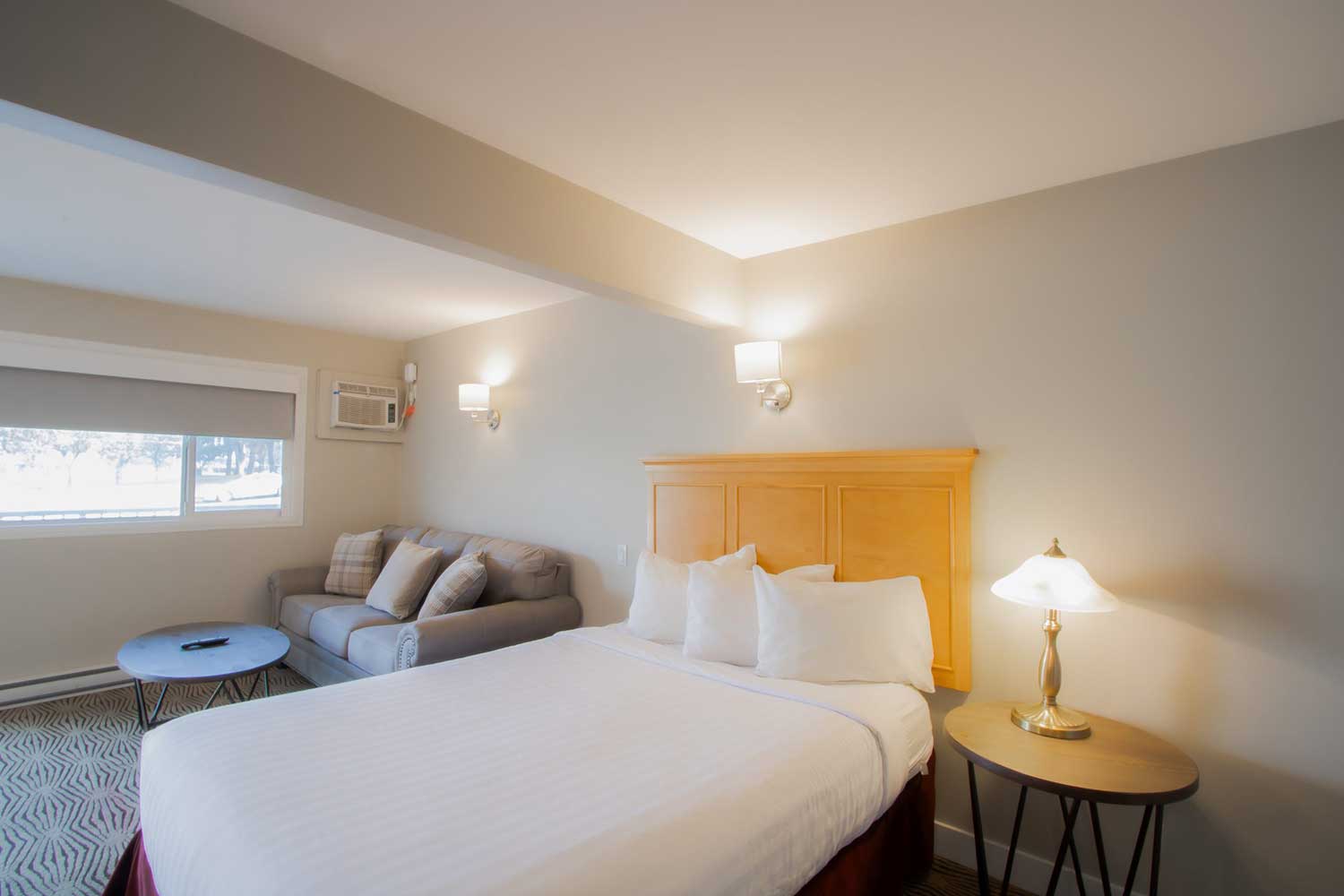 The queen bed in the studio kitchenette suite at Scott's Inn, a sofa in the background.