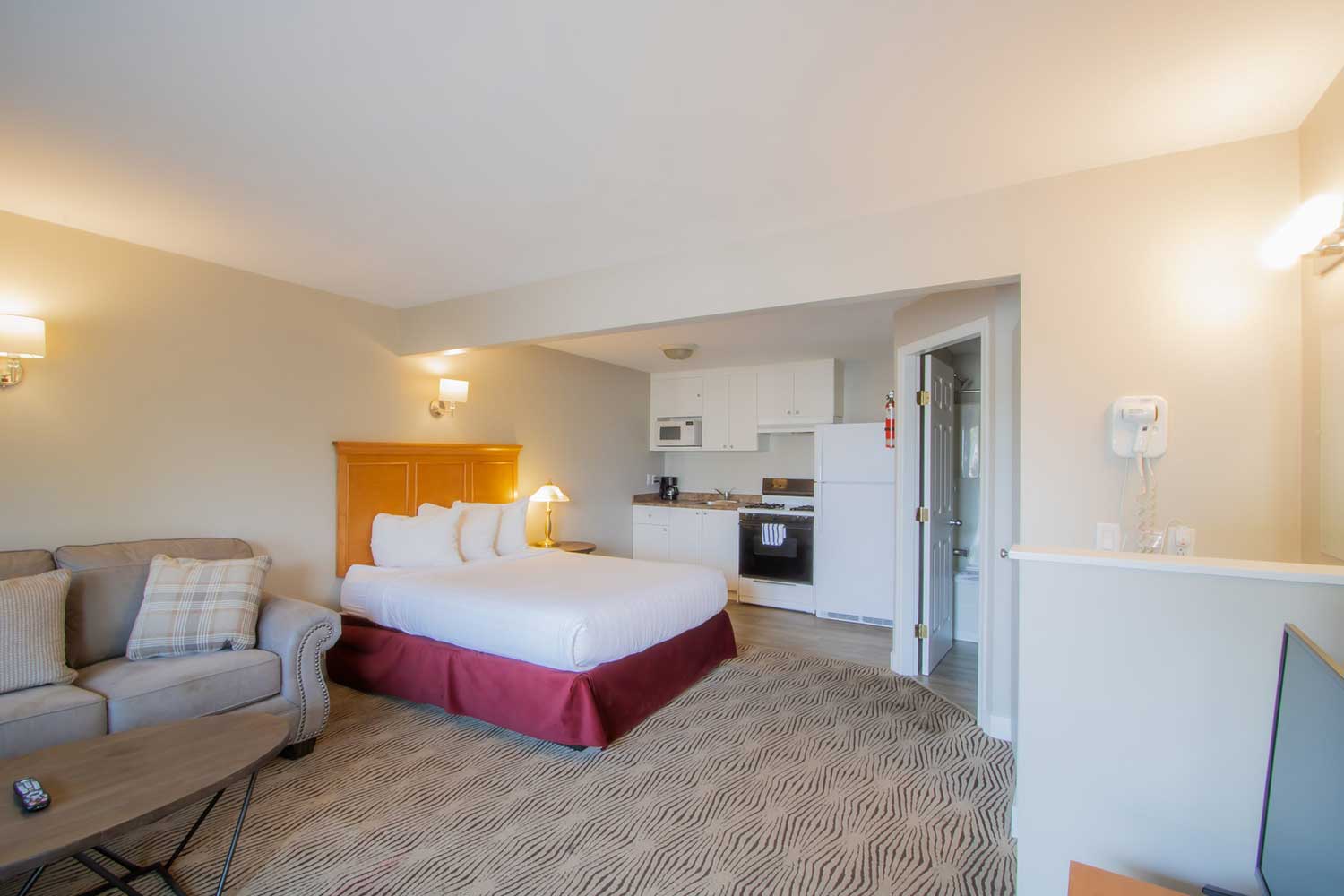 The queen bed of the studio kitchenette at Scott's Inn, the kitchenette in the background behind the bed.