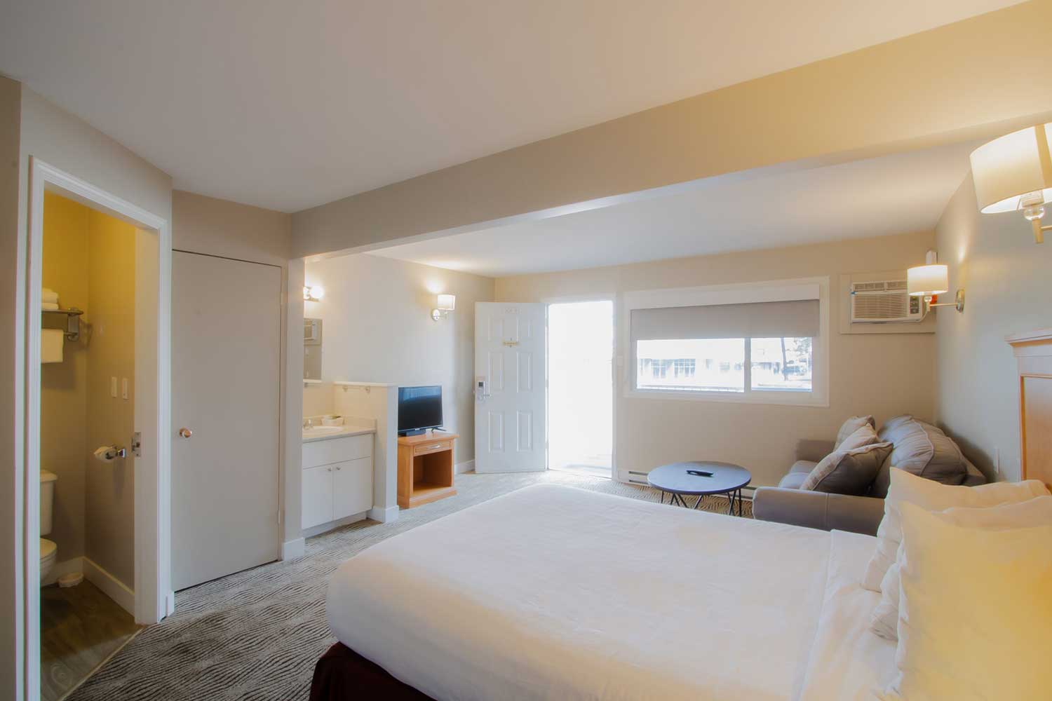 A studio kitchenette bedroom, with view to the sofa, which faces a flat-screened TV.
