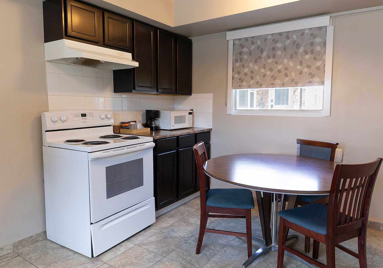 A kitchenette, complete with a microwave, stove, and oven, with a small dining table.