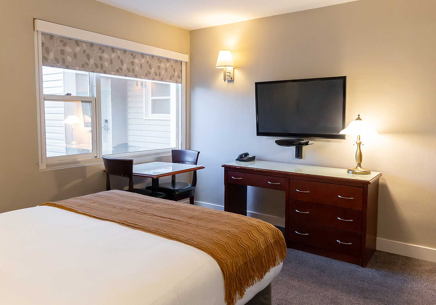 The queen bed facing a flat-screen TV in a suite at Scott's Inn.