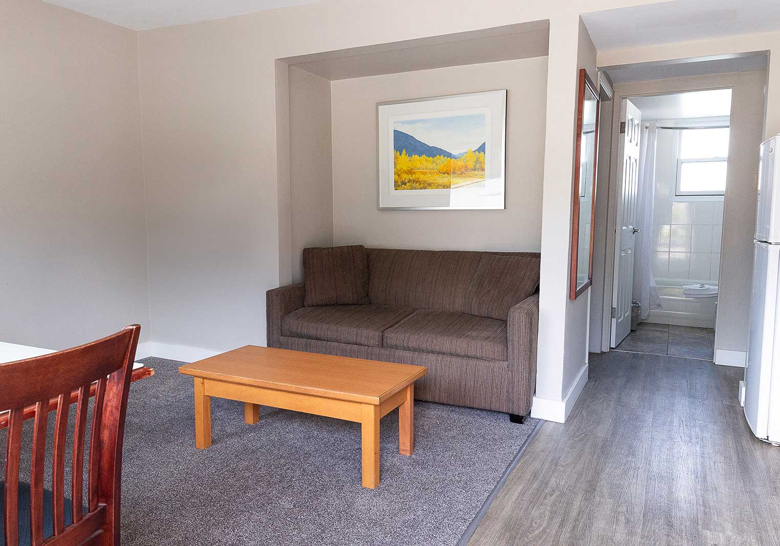 A sofa and view into the bathroom of a queen kitchenette suite at Scott's Inn.