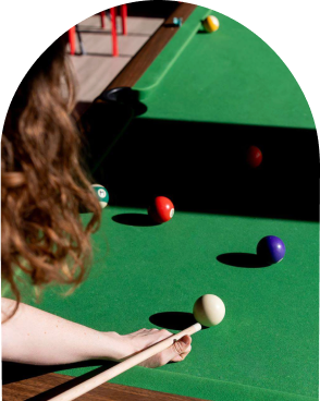 An arched shape of a woman hitting a billiard ball in the rec room at Scott's Inn.